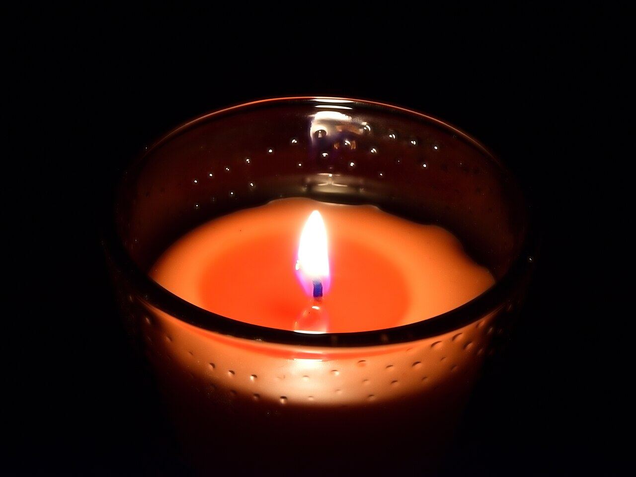 A lit soy candle glowing in a dark room